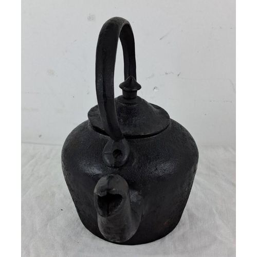 35 - A cast iron kettle with a curved handle and spout. Vintage blackened finish.