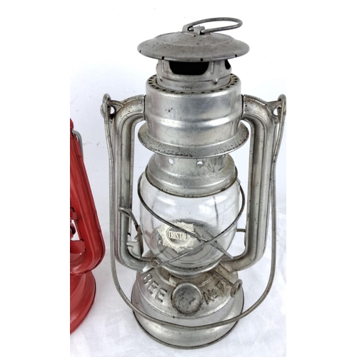 56 - Set of two vintage hurricane lanterns, featuring a red Moon R Light lantern and a silver-tone Free J... 