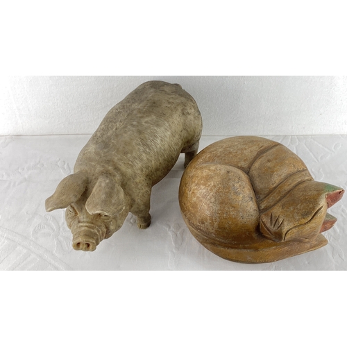 2 - Wooden animal carvings include a detailed pig and a sleeping cat with a naturalistic finish.