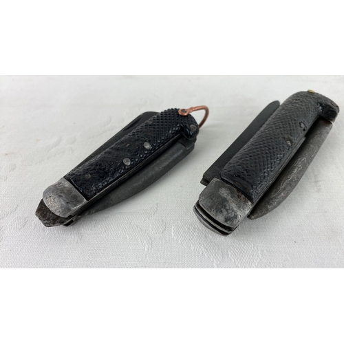 30 - Pair of vintage folding knives have textured black handles and rusted steel blades. They feature a d... 