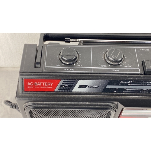 57 - Portable radio/cassette player with built-in AC transformer, featuring volume and tone controls, mul... 