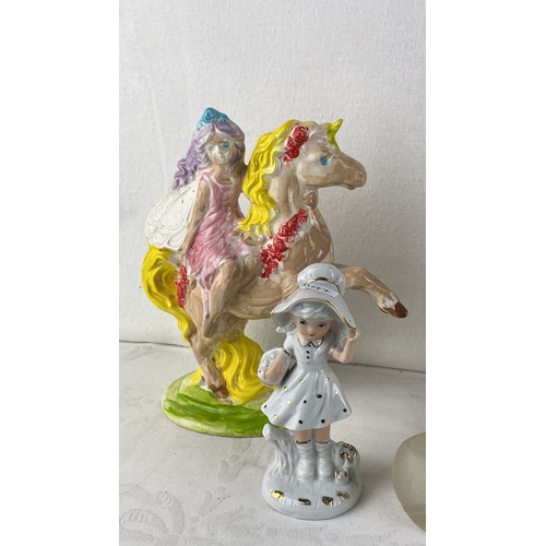 58 - Collection of decorative figurines including porcelain girls, an elderly woman, a unicorn and fairy,... 