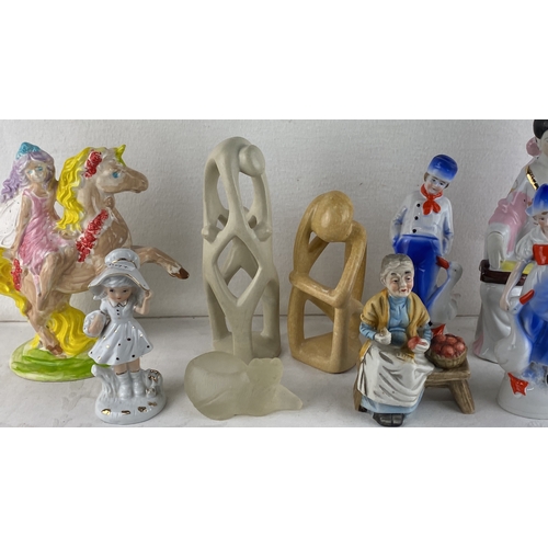 58 - Collection of decorative figurines including porcelain girls, an elderly woman, a unicorn and fairy,... 