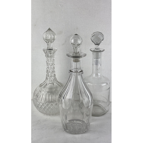 61 - Set of three vintage crystal decanters with cut-glass stoppers featuring ornate and clear designs.