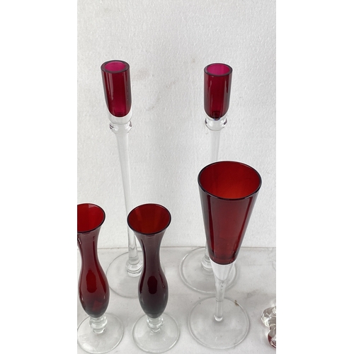 69 - Collection of ruby-red glass vases and champagne flutes with transparent bases, featuring elegant, v... 