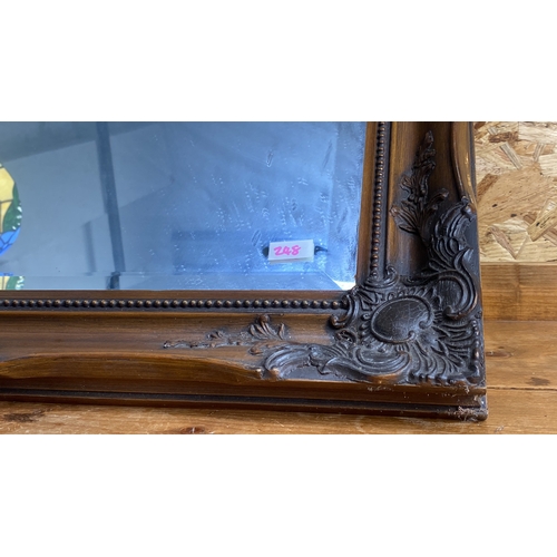 248 - Wall mirror featuring a carved wooden frame with intricate floral and scroll motifs.