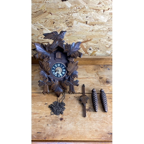 249 - Wooden cuckoo clock with carved maple leaf design, two pinecone weights, chain, and pendulum.