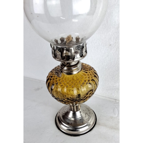 122 - Amber glass oil lamp features a clear glass chimney and metal base. It includes an intricately desig... 