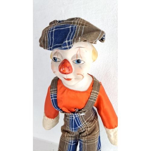 123 - Vintage clown doll with cloth overalls and cap, featuring a painted porcelain face. Includes an addi... 