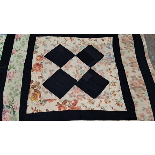 151 - Quilt features a floral pattern accented with black geometric designs, made from mixed fabrics.