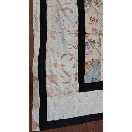 152 - Patchwork quilt features a variety of floral and geometric fabric pieces with contrasting black bord... 