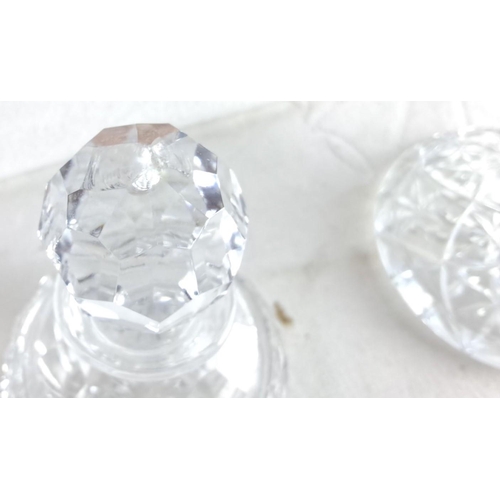 175 - Pair of cut glass decanters with faceted stoppers, featuring intricate starburst patterns.