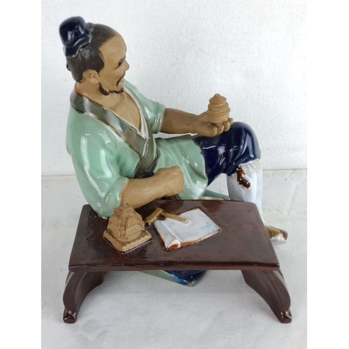 176 - Hand-painted porcelain figurine of an ancient Chinese scholar seated at a desk, holding a small arti... 