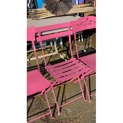 421 - Set of four pink metal folding garden chairs with decorative cut-out backs.