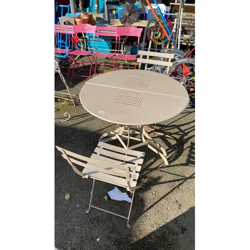 438 - Set includes a beige metal round table with perforated detailing and two matching folding chairs wit... 