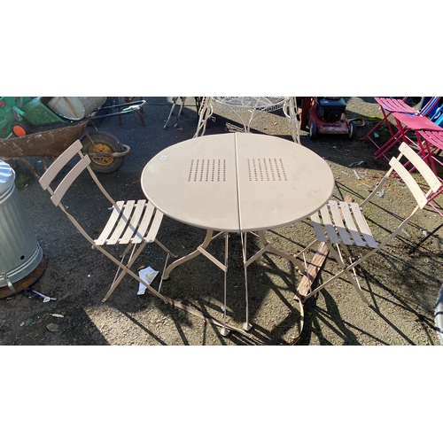 438 - Set includes a beige metal round table with perforated detailing and two matching folding chairs wit... 