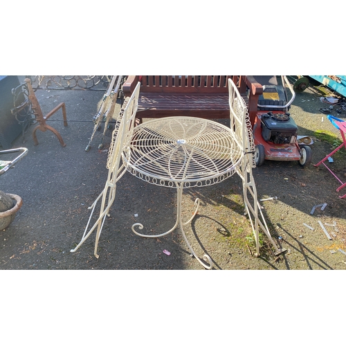 439 - wrought iron garden table with folding chairs, featuring intricate circular lattice work.