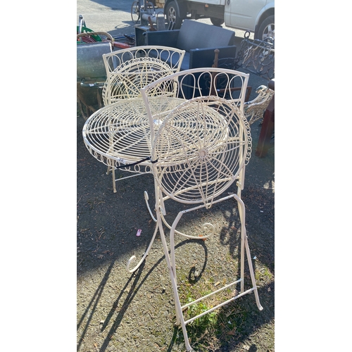 439 - wrought iron garden table with folding chairs, featuring intricate circular lattice work.