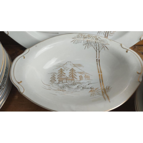 364 - Porcelain tea and dinner service set features a delicate gold landscape motif with houses and bamboo... 