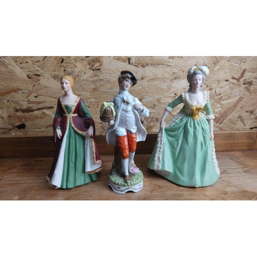 369 - Set of three porcelain figurines in period attire. The figures feature intricate detailing and vibra... 