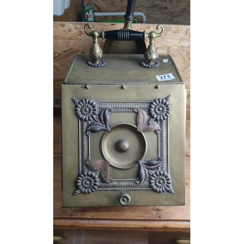 371 - Antique brass and copper coal scuttle with floral and leaf design, featuring a black wooden handle a... 