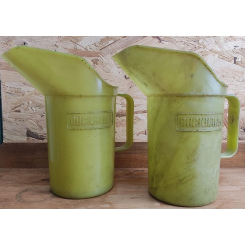 387 - Pair of vintage Duckhams oil jugs in yellow plastic, featuring classic branding.