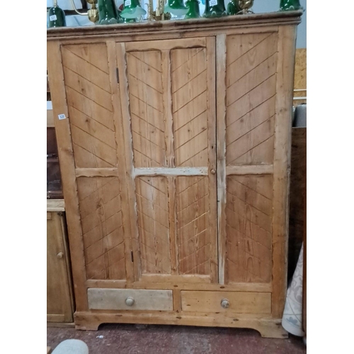 320 - Antique wooden wardrobe featuring chevron pattern doors and two drawers, made from pine. Early 20th-... 