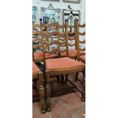 360 - Set of six oak ladder-back dining chairs with upholstered red seats.