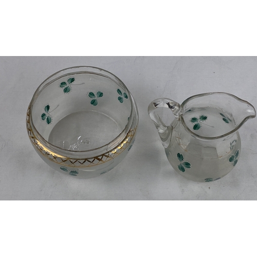 34 - Hand-painted glass creamer and sugar bowl set, decorated with green floral motifs and gold trim acce... 