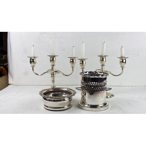 63 - Silver plated candelabra with two matching coasters and a wine bottle holder.