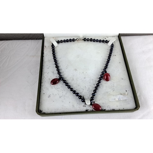 59 - Black bead necklace with red gemstone pendants, set in a classic style within a presentation box.