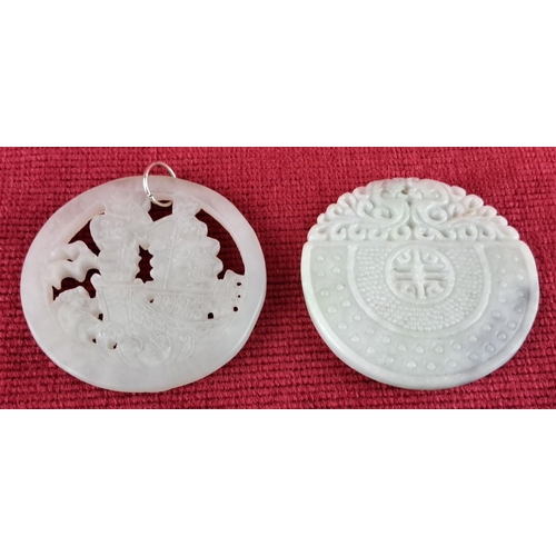 74 - Two intricately carved white jade pendants featuring traditional Chinese motifs.