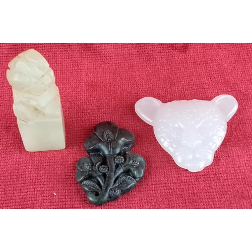 79 - Set of three carved jade pieces, featuring a lion, floral motif, and animal head.