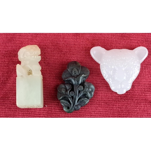 79 - Set of three carved jade pieces, featuring a lion, floral motif, and animal head.