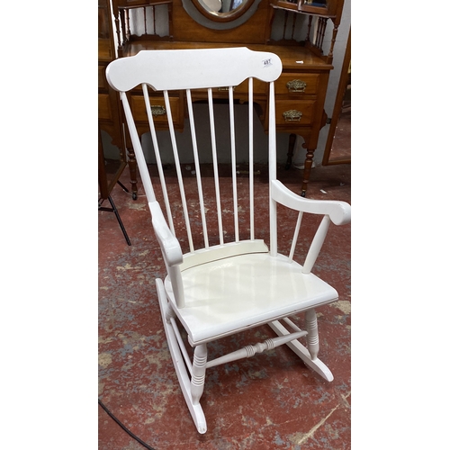 487 - White wooden rocking chair featuring spindled back and armrests. Classic design.