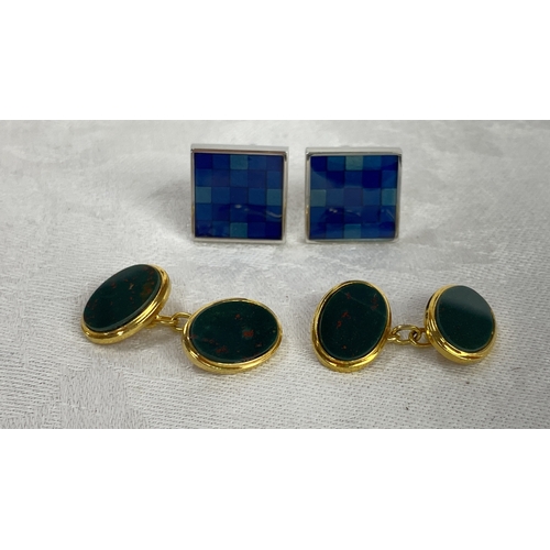 109 - Pair of cufflink sets featuring blue checkered enamel and gold-tone metal with green stone inset.