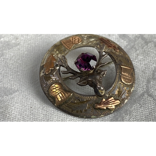 116 - Scottish silver brooch features a stag motif, with amethyst stone, copper and silver detailing.