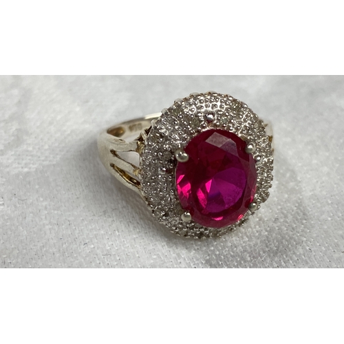 121 - Sterling silver ring features a vivid oval-shaped pink gemstone, accented by diamond-like stones, st... 