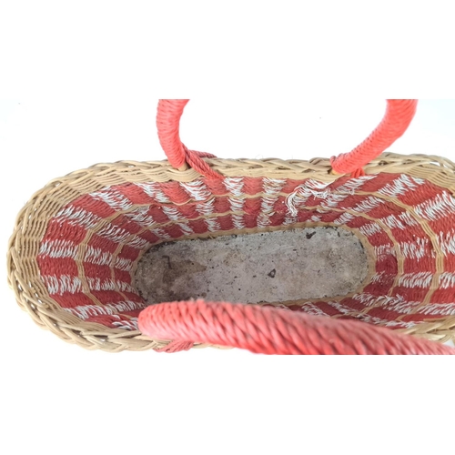 25 - Woven basket features red, white, and natural tones with braided handles.