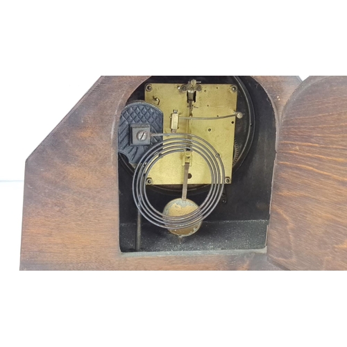 31 - Art Deco oak mantel clock features brass movement and a circular dial, with intricate wood detailing... 