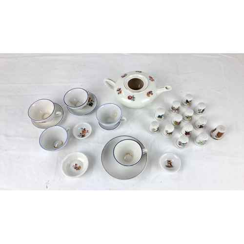 49 - Porcelain dolls tea set with floral patterns, including teapot, cups, saucers, and decorative thimbl... 