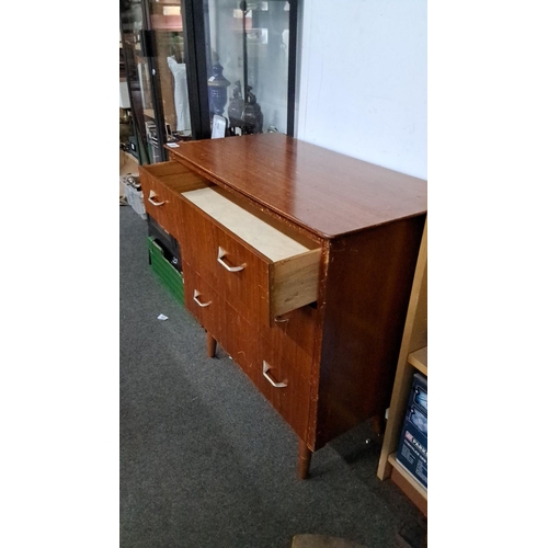 69 - Mid-Century Modern teak veneer chest of drawers with tapered legs and metal handles.