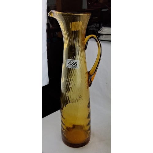 436 - Large Amber-colored glass pitcher with a ribbed texture, a curved handle, and a flared spout.