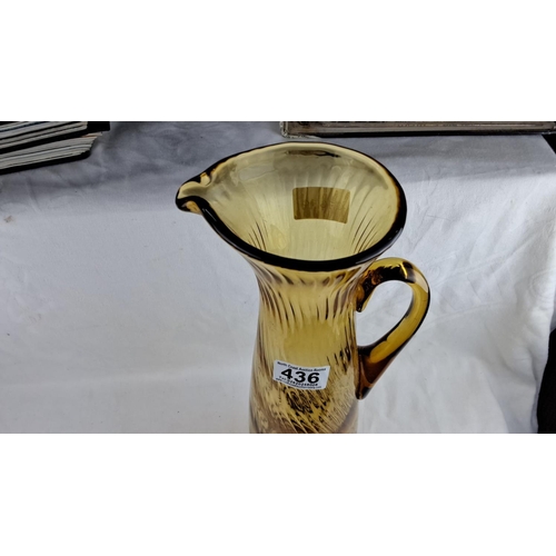 436 - Large Amber-colored glass pitcher with a ribbed texture, a curved handle, and a flared spout.