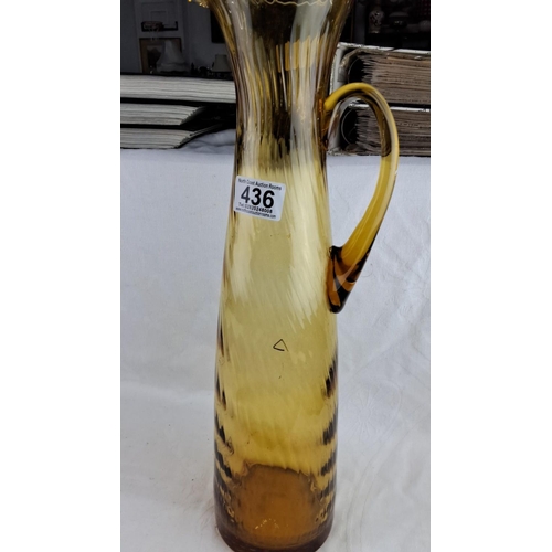 436 - Large Amber-colored glass pitcher with a ribbed texture, a curved handle, and a flared spout.