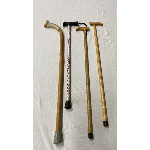 445 - Collection of four walking canes, featuring natural wood and a vibrant polka dot design. Styles vary... 