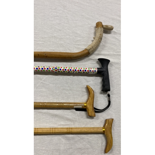 445 - Collection of four walking canes, featuring natural wood and a vibrant polka dot design. Styles vary... 