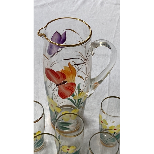 448 - Hand-painted glass pitcher and tumblers set, featuring vibrant floral and butterfly motifs with gold... 