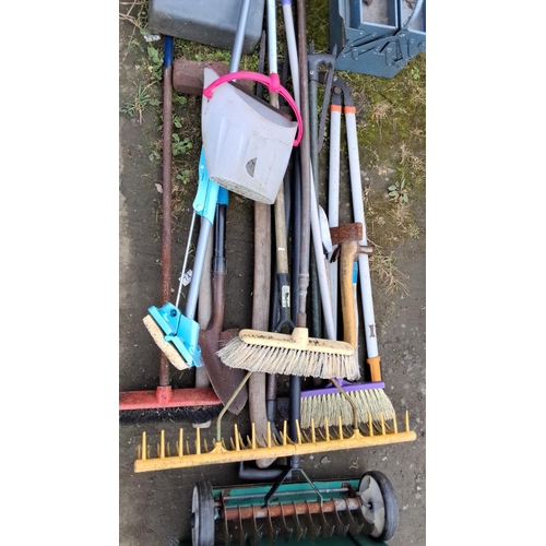 22 - Assorted garden tools and equipment, including brooms, rakes, shovels, and a large green plastic too... 