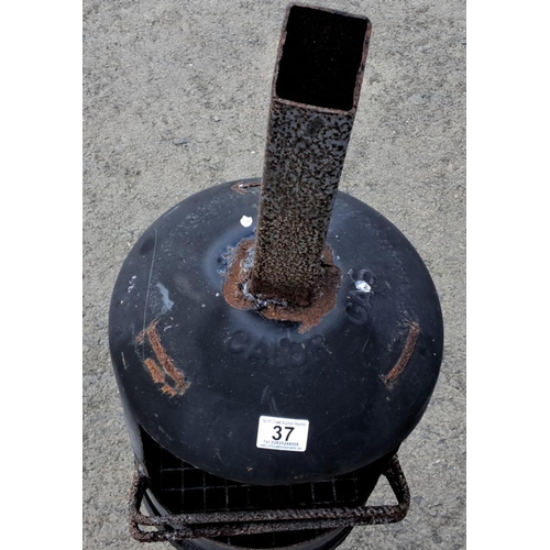 37 - Repurposed metal chiminea with grill, featuring a cylindrical design and elevated on sturdy legs.